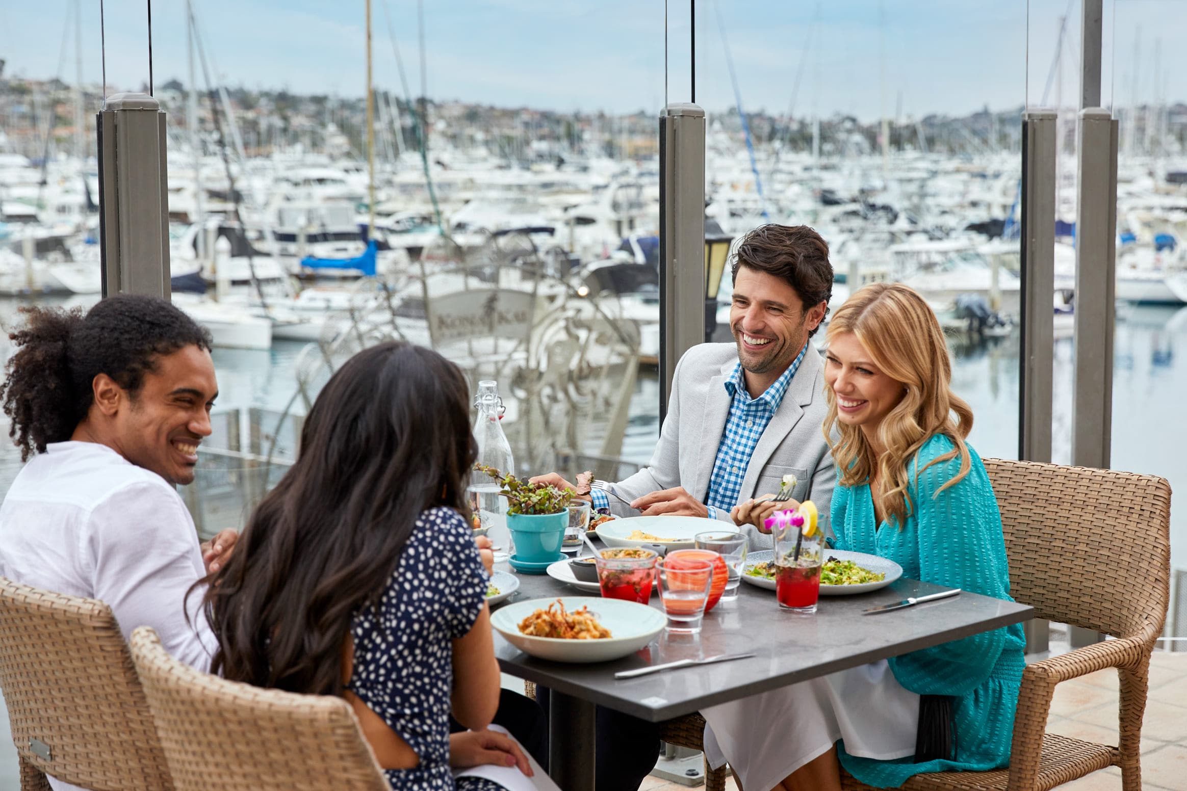A group of four people eating on Vessels patio next to the water at Kona Kai